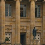 Fachada de um prédio de tribunal, com colunas e uma estátua na entrada.